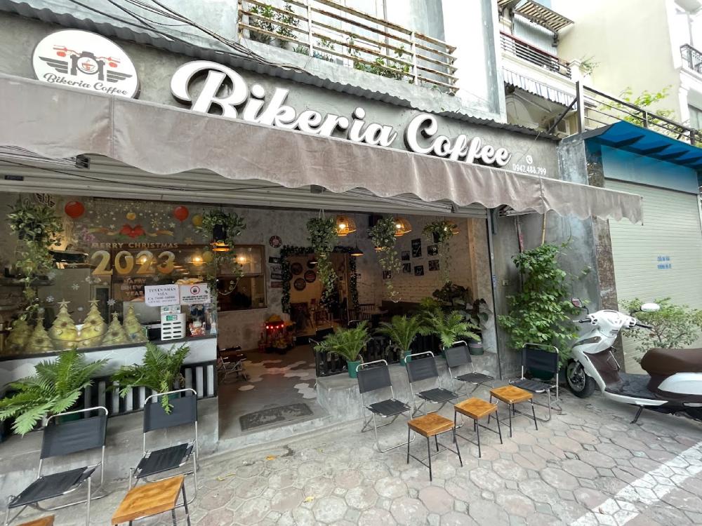 Khám Phá 11 Quán Cafe Đội Cấn Tuyệt Vời Cho Thư Giãn Và Làm Việc 18 Mặt tiền quán cà phê với bảng hiệu lớn, cây xanh và xe máy đỗ phía trước, trang trí Giáng sinh năm 2023.