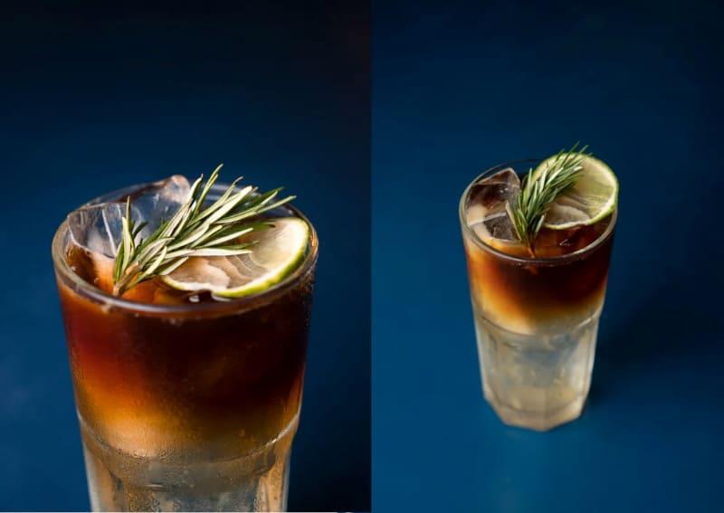 Ly cocktail đặt trên nền xanh, trang trí lát chanh, lá hương thảo và đá viên.