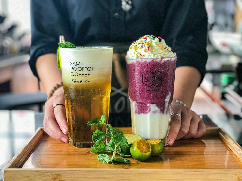 Khám Phá 7 Quán Cafe Tuyệt Đẹp Ở Ngã Tư Sở: View Đẹp, Đồ Uống Ngon, Giá Phải Chăng 16 Hai ly nước uống mát lạnh trên khay gỗ với trang trí chanh tươi và lá bạc hà.
