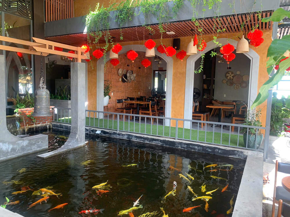 Top 5 Quán Cafe Cá Koi Đẹp Không Thể Bỏ Qua Tại Quy Nhơn 10 Ao cá koi bên trong quán cà phê, trang trí đèn lồng đỏ và cây xanh, không gian ấm cúng và thư giãn.