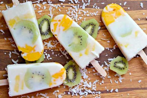 Kem que trái cây với kiwi và xoài trên nền gỗ, rắc dừa nạo bên trên.