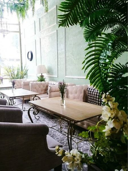 Qu&aacute;n c&agrave; ph&ecirc; trang tr&iacute; phong c&aacute;ch cổ điển với b&agrave;n ghế gỗ, c&acirc;y xanh v&agrave; hoa, &aacute;nh s&aacute;ng tự nhi&ecirc;n từ cửa sổ lớn.