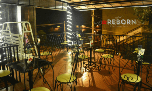 Quán cà phê sân thượng với bàn ghế kim loại, trang trí đèn dây sáng lung linh vào buổi tối.