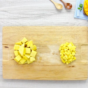 Hai phần xo&agrave;i cắt hạt lựu với k&iacute;ch thước kh&aacute;c nhau đặt tr&ecirc;n thớt gỗ, b&ecirc;n cạnh c&oacute; hai muỗng gỗ.