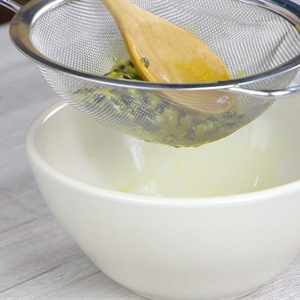 Dụng cụ lọc đang được sử dụng để lọc hạt từ hỗn hợp m&agrave;u v&agrave;ng v&agrave;o trong một chiếc b&aacute;t trắng.