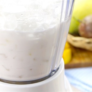 M&aacute;y xay sinh tố đang chứa hỗn hợp sữa v&agrave; đ&aacute;, chuẩn bị cho một m&oacute;n đồ uống.