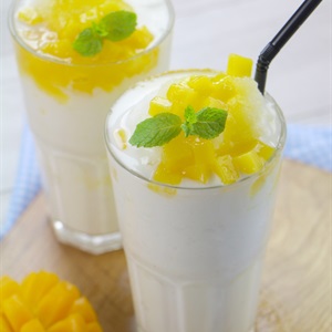 Hai ly sinh tố xo&agrave;i trang tr&iacute; l&aacute; bạc h&agrave;, đặt tr&ecirc;n b&agrave;n gỗ, với ống h&uacute;t đen.