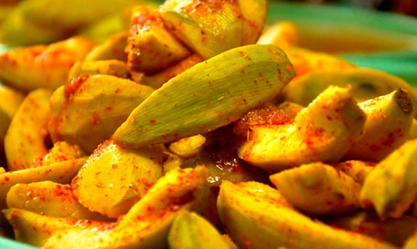 Đĩa xoài xanh cắt miếng, trộn muối ớt, bày biện trên nền đĩa xanh.