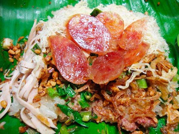 Đĩa xôi được trình bày trên lá chuối, có lạp xưởng, ruốc, hành phi và các loại thịt xé nhỏ.