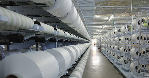 D&acirc;y chuyền sản xuất với c&aacute;c cuộn vải lớn xếp h&agrave;ng trong nh&agrave; m&aacute;y s&aacute;ng sủa, hiện đại.