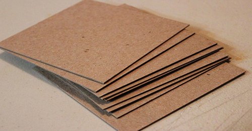 Một chồng tấm b&igrave;a cứng m&agrave;u n&acirc;u xếp chồng l&ecirc;n nhau tr&ecirc;n bề mặt phẳng.