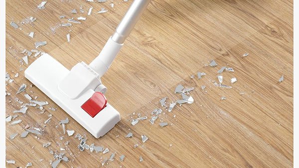 M&aacute;y h&uacute;t bụi đang h&uacute;t mảnh vỡ thủy tinh tr&ecirc;n s&agrave;n gỗ.