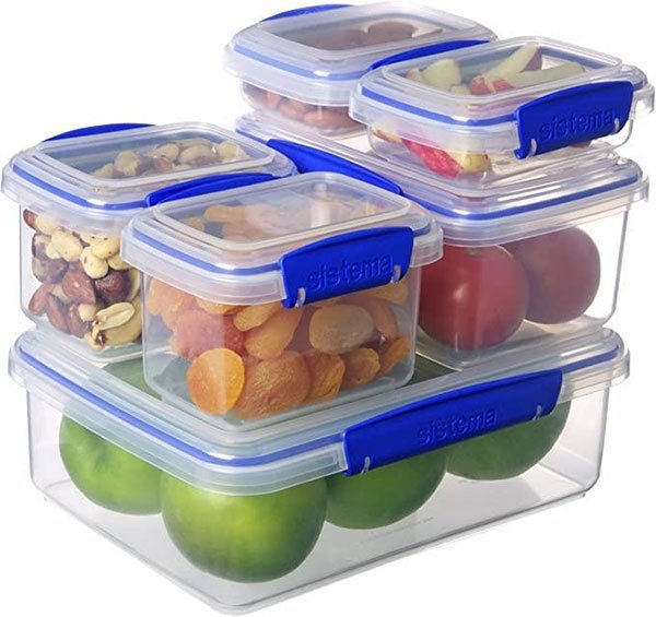 Các hộp nhựa trong suốt với nắp xanh, chứa trái cây và hạt khô, xếp chồng lên nhau.