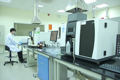 Ph&ograve;ng th&iacute; nghiệm với thiết bị hiện đại v&agrave; một người đang l&agrave;m việc, mặc &aacute;o bảo hộ v&agrave; đeo khẩu trang.