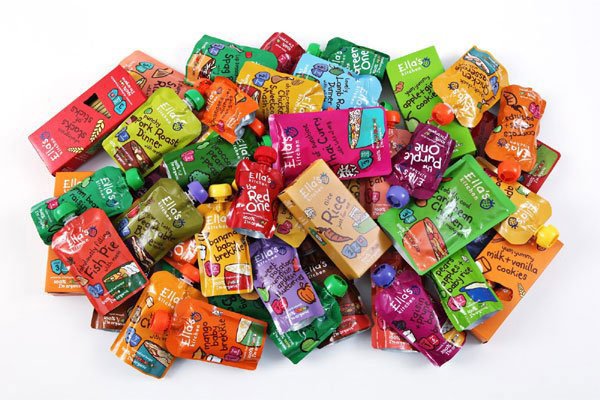 Nhiều túi đồ ăn trẻ em nhiều màu sắc nằm chồng lên nhau trên nền trắng.