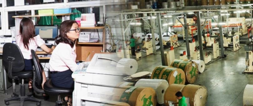 Văn ph&ograve;ng v&agrave; xưởng sản xuất với nh&acirc;n vi&ecirc;n l&agrave;m việc, m&aacute;y t&iacute;nh, thiết bị v&agrave; cuộn giấy lớn trong kh&ocirc;ng gian c&ocirc;ng nghiệp.