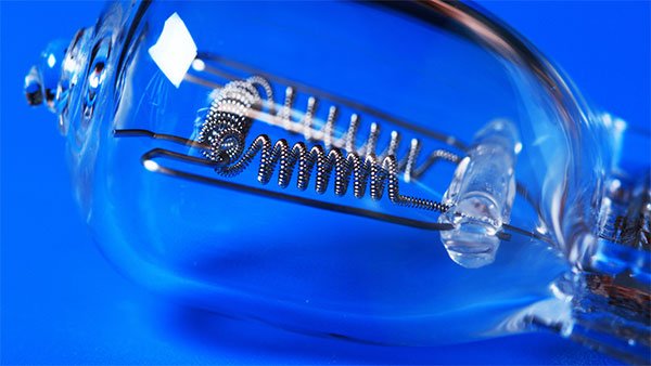 Bóng đèn dây tóc cận cảnh trên nền xanh, hiển thị chi tiết cuộn dây và bóng thủy tinh.