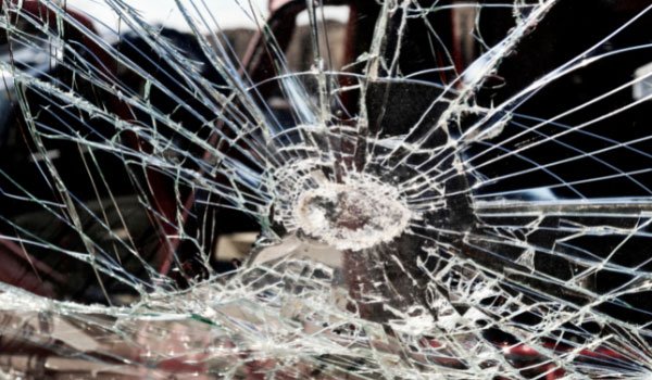 Kính ô tô bị vỡ, với nhiều vết nứt tỏa ra từ trung tâm, tạo thành một mô hình giống mạng nhện.