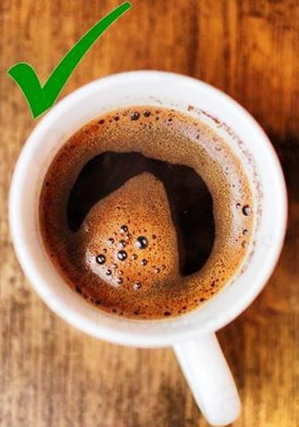 Khám Phá Bí Thuật Cảm Nhận Hương Vị Chân Thực Từ Tách Cà Phê Nguyên Bản và Cổ Điển 7 Tách cà phê với bọt nổi trên bề mặt, có dấu kiểm màu xanh lá ở góc trên trái, đặt trên bàn gỗ.