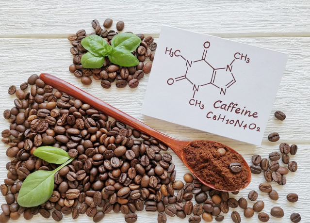 Hạt c&agrave; ph&ecirc;, bột c&agrave; ph&ecirc; tr&ecirc;n th&igrave;a, l&aacute; xanh, c&ocirc;ng thức h&oacute;a học caffeine tr&ecirc;n giấy.