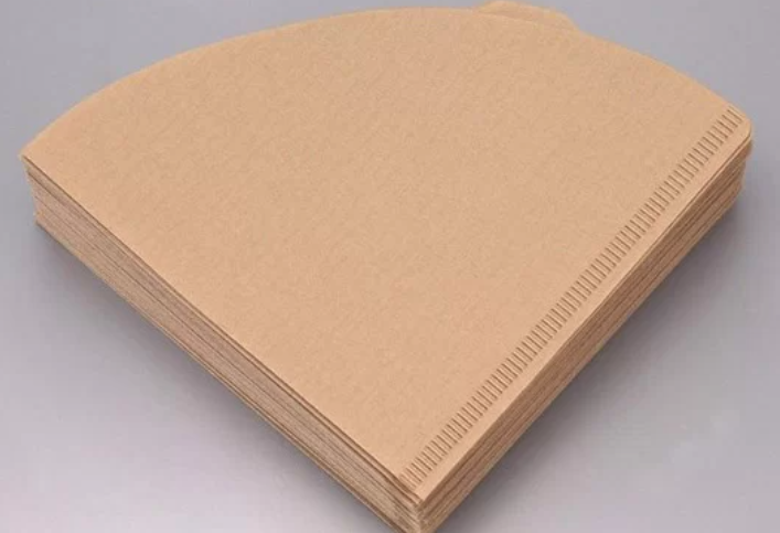 Một chồng giấy lọc c&agrave; ph&ecirc; m&agrave;u n&acirc;u, h&igrave;nh n&oacute;n, xếp gọn g&agrave;ng tr&ecirc;n bề mặt trơn nhẵn.