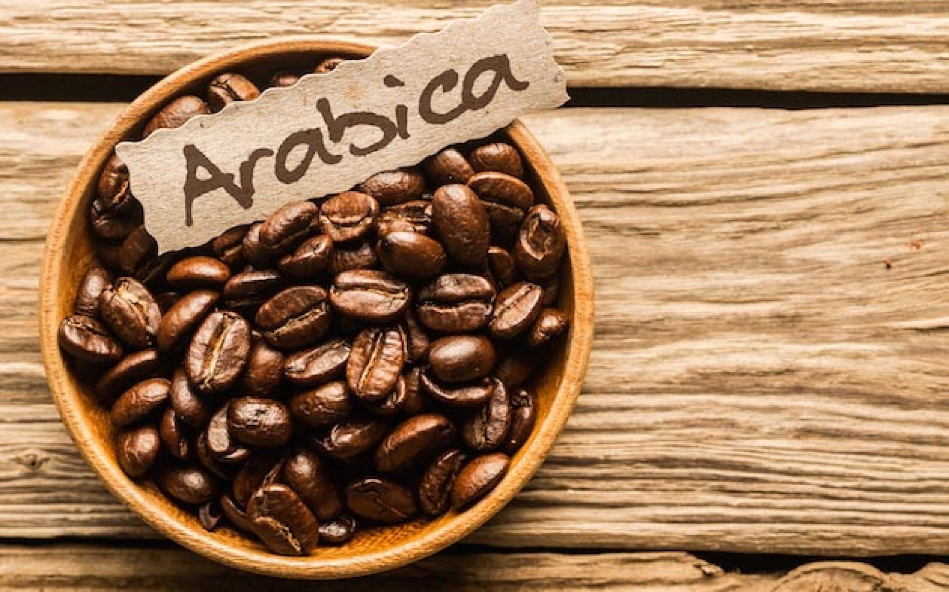 T&ocirc; c&agrave; ph&ecirc; hạt Arabica tr&ecirc;n b&agrave;n gỗ với tấm thẻ ghi t&ecirc;n loại c&agrave; ph&ecirc;.