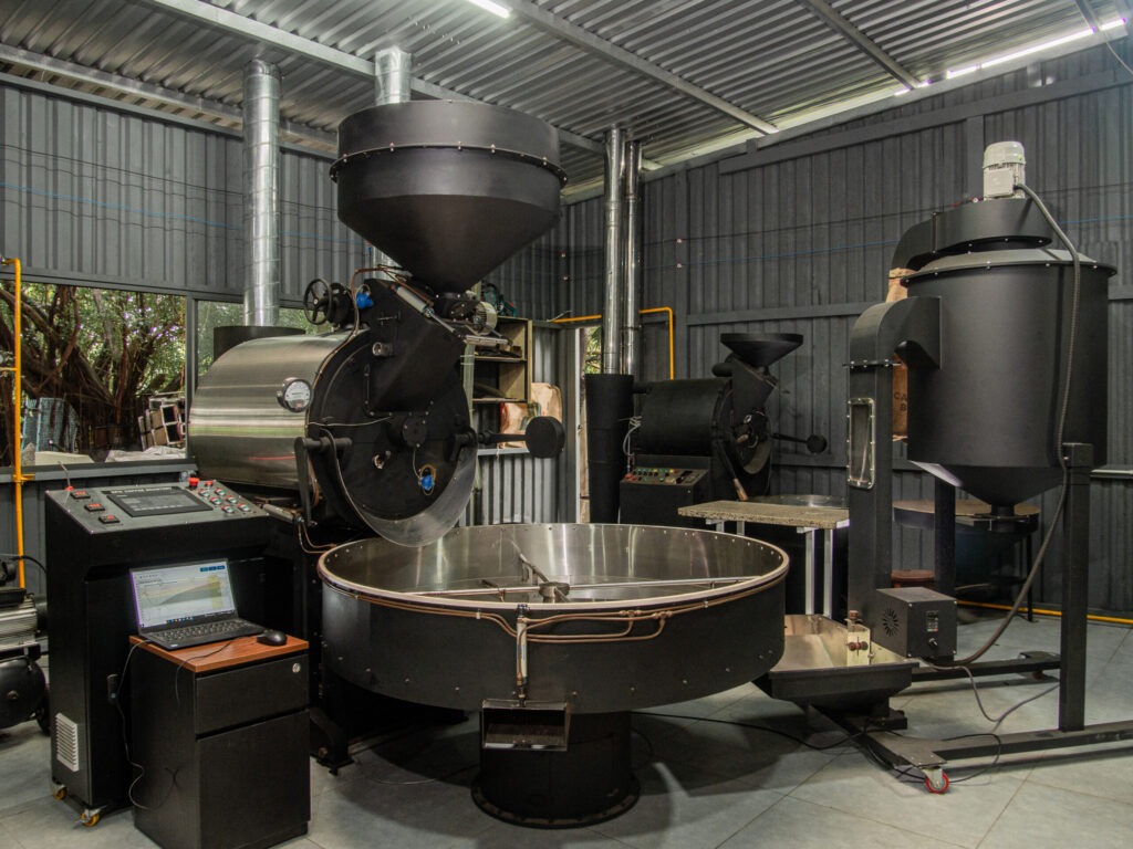 M&aacute;y rang c&agrave; ph&ecirc; c&ocirc;ng nghiệp trong nh&agrave; xưởng với c&aacute;c thiết bị v&agrave; bảng điều khiển hiện đại.