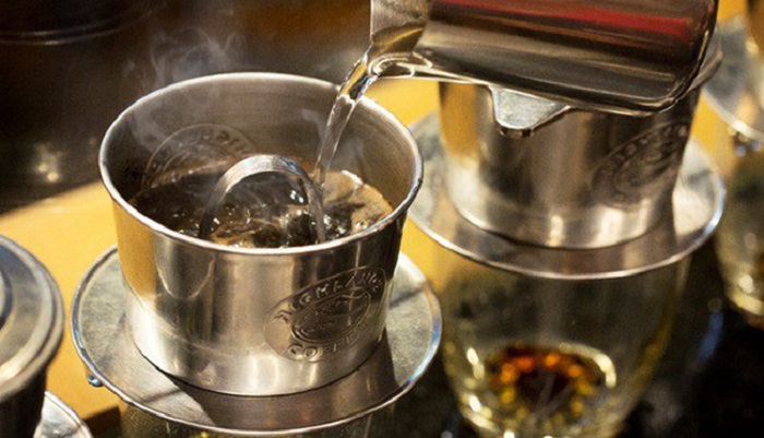 Nước n&oacute;ng đang được r&oacute;t v&agrave;o phin pha c&agrave; ph&ecirc; bằng kim loại, chuẩn bị cho qu&aacute; tr&igrave;nh pha c&agrave; ph&ecirc; phin truyền thống.