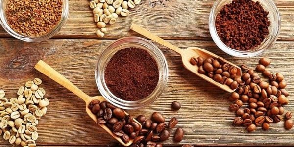 Khám phá công thức cà phê tuyệt đỉnh: Bí quyết bùng nổ doanh thu không thể cưỡng lại! 6 Các loại hạt cà phê và bột cà phê trên nền gỗ, với thìa và hũ thủy tinh đựng nguyên liệu.