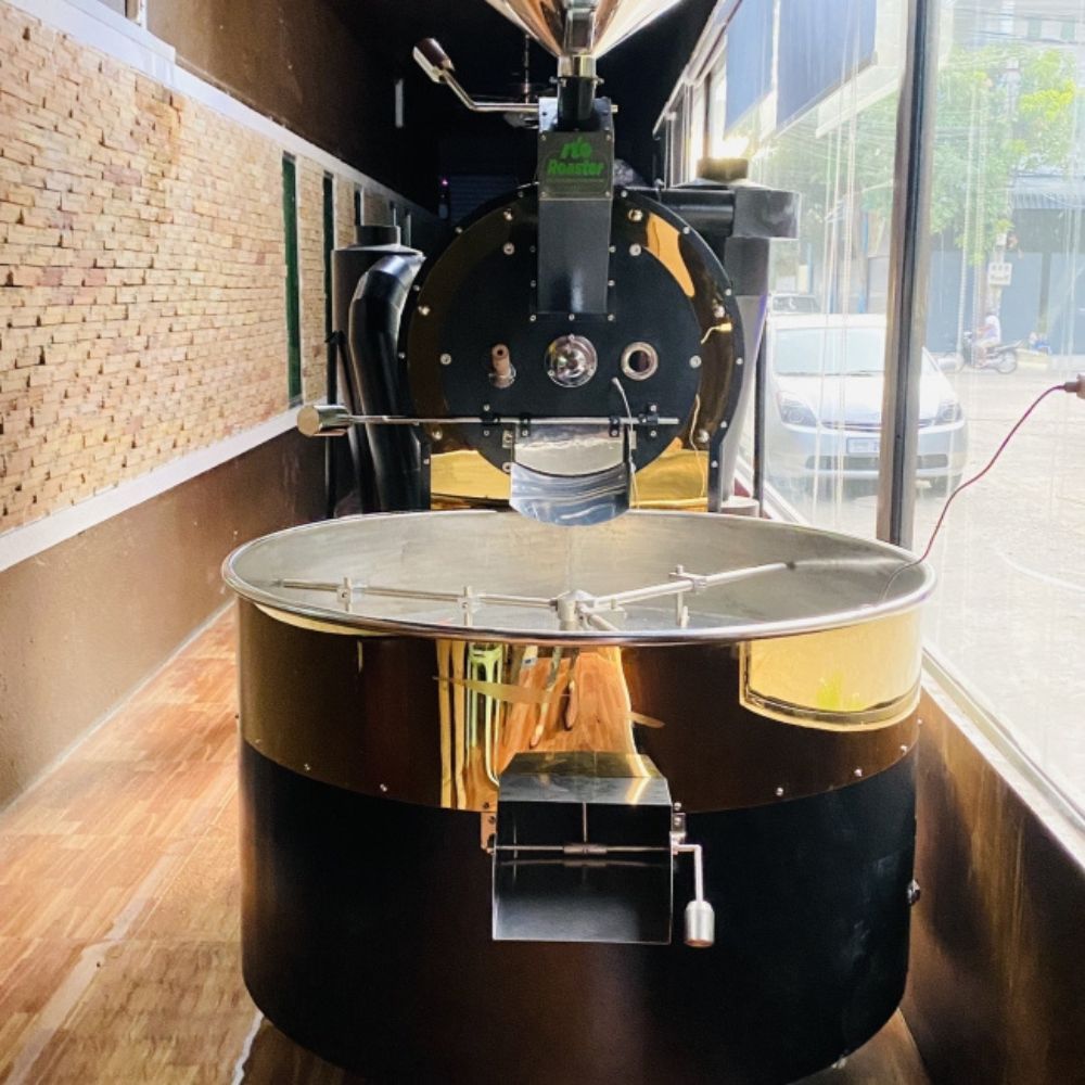 M&aacute;y rang c&agrave; ph&ecirc; lớn đặt trong ph&ograve;ng với tường gạch v&agrave; cửa sổ k&iacute;nh nh&igrave;n ra b&ecirc;n ngo&agrave;i.