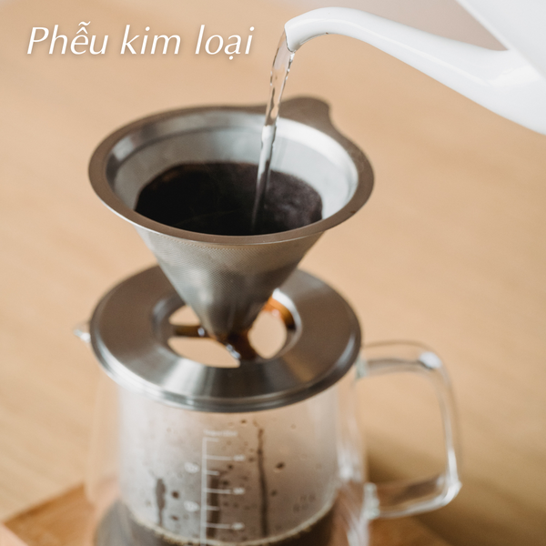 Chinh phục Nghệ Thuật Pha Cà Phê Nhỏ Giọt Đỉnh Cao (Phần III) 6 Nước đang được đổ qua phễu kim loại chứa cà phê, phía dưới là bình thủy tinh.