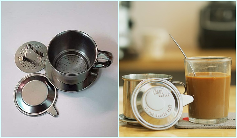 Bộ pha cà phê phin bằng kim loại bên trái và ly cà phê sữa bên phải trên bàn gỗ.