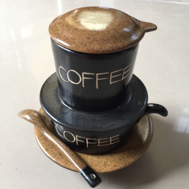 Bộ phin cà phê gốm màu nâu đen, gồm cốc, nắp và thìa, có chữ "COFFEE" nổi bật.