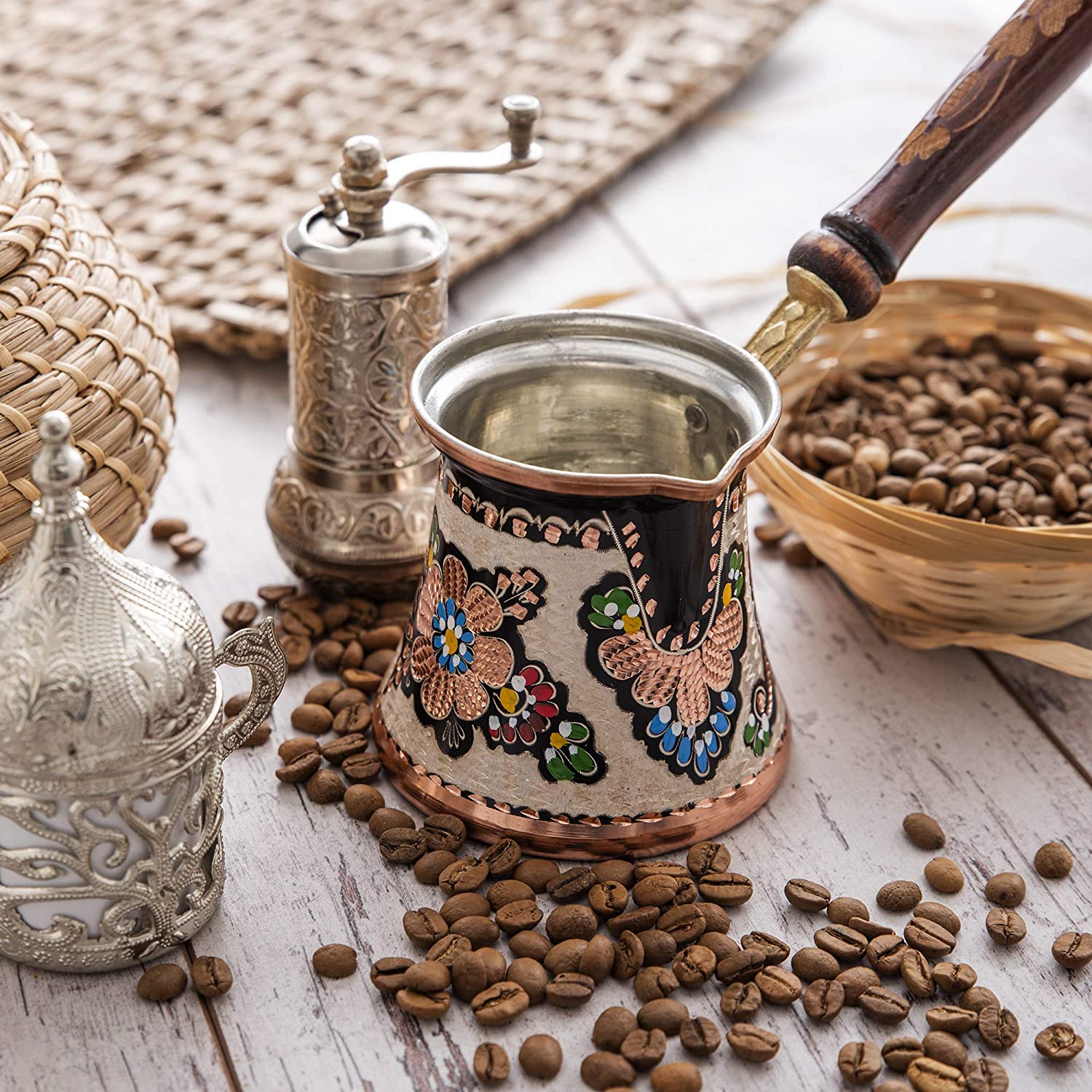 Bộ dụng cụ pha c&agrave; ph&ecirc; truyền thống với ấm hoa văn v&agrave; hạt c&agrave; ph&ecirc; xung quanh tr&ecirc;n b&agrave;n gỗ.