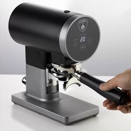 Máy pha cà phê hiện đại với tay cầm, có màn hình hiển thị số, đặt trên bề mặt phẳng màu trắng.