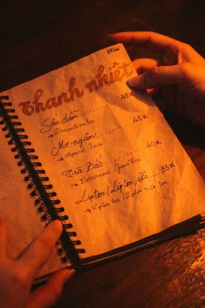 Cuốn sổ tay với menu đồ uống viết bằng tay, c&oacute; gi&aacute; tiền v&agrave; t&ecirc;n c&aacute;c loại nước tr&ecirc;n nền giấy n&acirc;u.