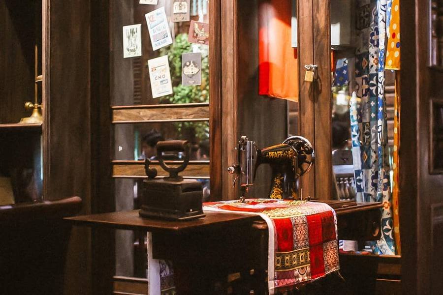 M&aacute;y may cổ điển đặt tr&ecirc;n b&agrave;n, b&ecirc;n cạnh b&agrave;n ủi, trong kh&ocirc;ng gian trang tr&iacute; với gương v&agrave; vải nhiều m&agrave;u.