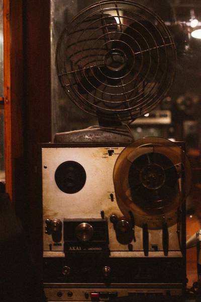 M&aacute;y ghi &acirc;m cổ điển với băng từ v&agrave; c&aacute;c n&uacute;t điều khiển, đặt trong kh&ocirc;ng gian &aacute;nh s&aacute;ng mờ.