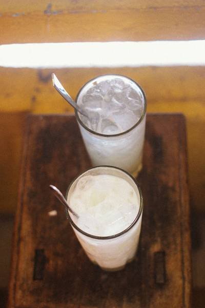 Hai ly nước đ&aacute; tr&ecirc;n b&agrave;n gỗ, mỗi ly c&oacute; một chiếc th&igrave;a kim loại.