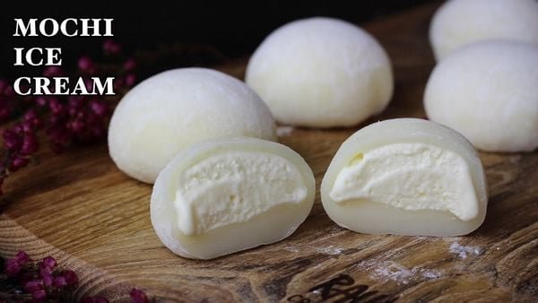 Bánh mochi kem đang được cắt đôi, bày trên thớt gỗ, nền tối, chữ "MOCHI ICE CREAM" bên trái.