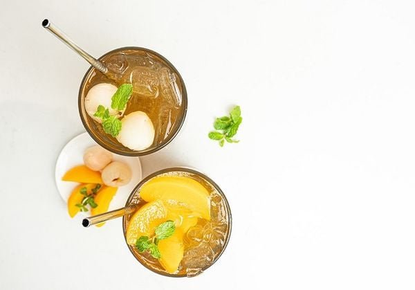 dsc05446-1603944619_1c6d4323a5154e7b9956fd31d3e3fad2_grande Hai ly trà trái cây trang trí bạc hà và trái cây tươi, đặt trên nền trắng kèm đĩa trái cây.