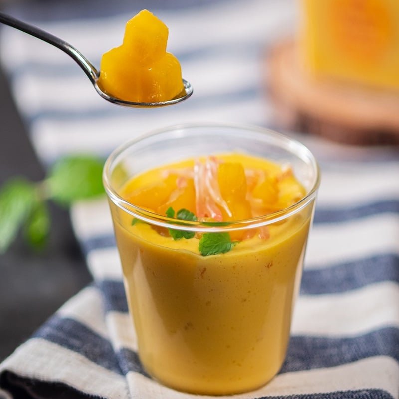 Ly kem xo&agrave;i với thạch v&agrave; l&aacute; bạc h&agrave;, một th&igrave;a kem được m&uacute;c l&ecirc;n, nền vải sọc xanh trắng.