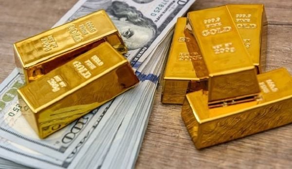 Các thỏi vàng nằm trên chồng tiền đô la Mỹ, đặt trên bề mặt gỗ.