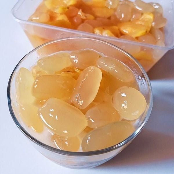 Ly và hộp chứa thạch trái cây màu vàng nhạt, đặt trên nền trắng.