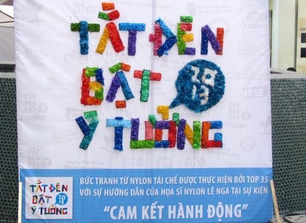 Biển quảng cáo sự kiện với dòng chữ đầy màu sắc làm từ chất liệu tái chế, kèm thông điệp bên dưới.