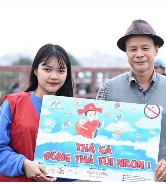 Hai người đứng cầm tấm biển với thông điệp bảo vệ môi trường, khuyến khích không sử dụng túi ni lông.