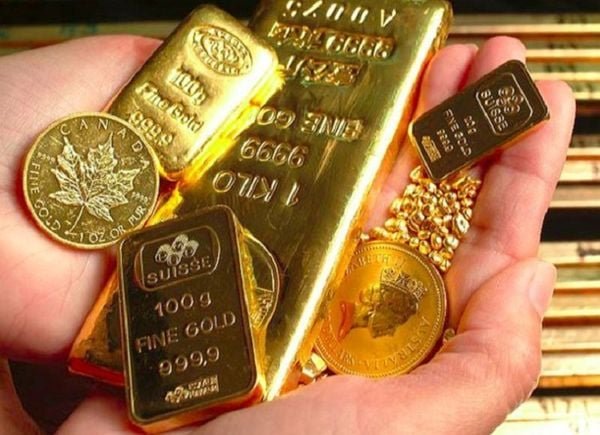 Một người đang cầm nhiều thỏi vàng và đồng xu vàng sáng bóng trong tay.