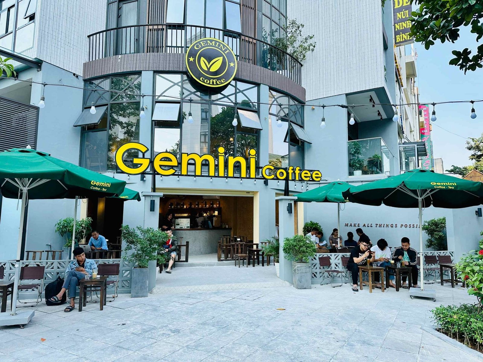 Top 32 thương hiệu nhượng quyền cafe siêu lợi nhuận 19 Quán cà phê với mái che xanh, có người ngồi uống nước ngoài trời; biển hiệu "Gemini Coffee" phía trên.