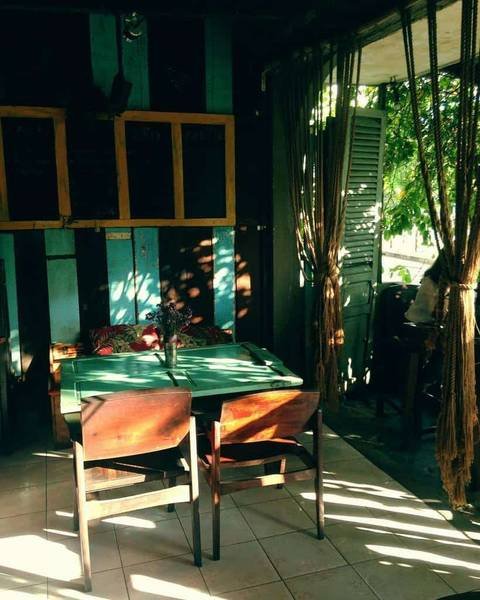 Qu&aacute;n c&agrave; ph&ecirc; nhỏ với b&agrave;n ghế gỗ, &aacute;nh s&aacute;ng tự nhi&ecirc;n chiếu qua r&egrave;m, kh&ocirc;ng gian xanh m&aacute;t v&agrave; y&ecirc;n tĩnh.