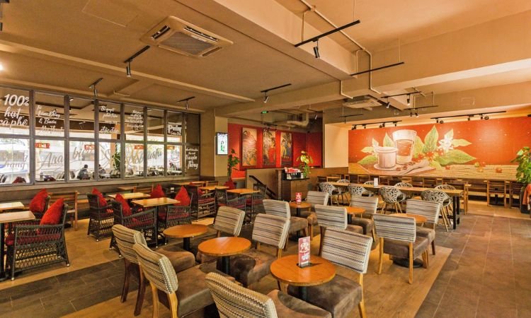 Qu&aacute;n c&agrave; ph&ecirc; hiện đại với b&agrave;n ghế gỗ, trang tr&iacute; tranh tường, &aacute;nh s&aacute;ng ấm c&uacute;ng.